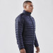 A navy blue puffer jacket featuring a zip front and a high collar, worn by a model. It has a logo on the side.