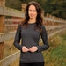 A woman models a long-sleeve, charcoal grey tee with a simple design, set against a natural outdoor backdrop.