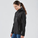 A woman wearing a black softshell jacket with a hood, featuring zippered pockets and a fitted design.