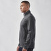 A man wearing a grey lightweight softshell jacket with a high collar and zippered pockets, featuring a logo.