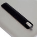 A metal pen in a black holder, placed on a grey surface, featuring a silver clip and end. A metal pen in a black holder, placed on a grey surface, featuring a silver clip and end.