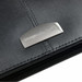 A black leather zippered compendium with a metallic logo embellishment. A black leather zippered compendium with a metallic logo embellishment.