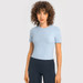 A light blue short sleeve yoga top with a fitted design, paired with dark leggings. The top features a logo.