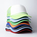 A stack of vibrant trucker caps in various colours, featuring mesh backs and curved visors, with a logo present.