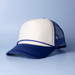 A trucker cap in cream and navy blue with a mesh back and a curved brim. It features a logo on the front.