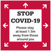 A floor decal sticker in red and white, featuring arrows and a message about maintaining social distance.