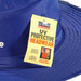 A blue Poly Viscose Slouch Hat with a tag indicating UV protective features and a logo. A blue Poly Viscose Slouch Hat with a tag indicating UV protective features and a logo.