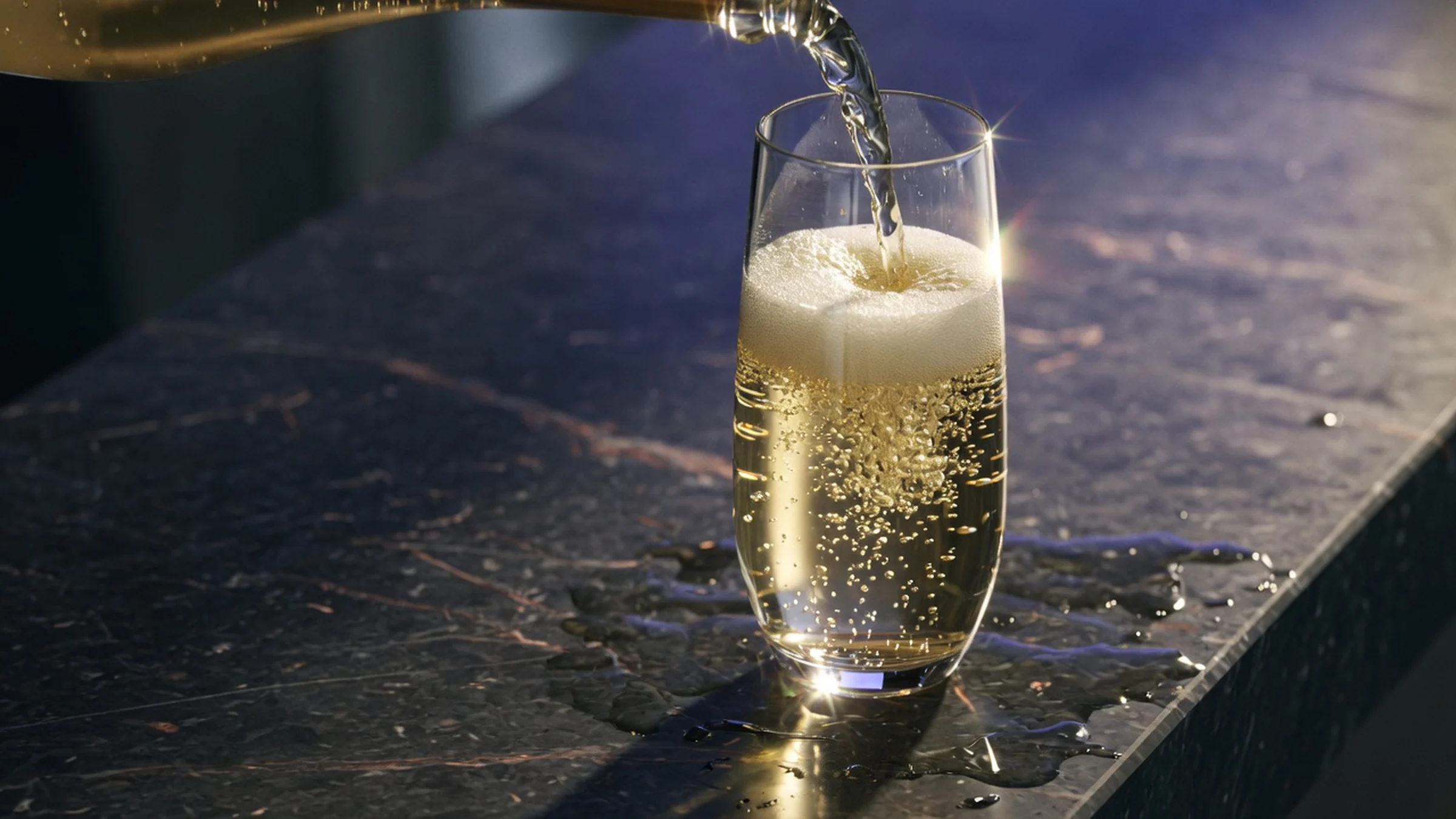Sparkling wine pouring into an elegant flute at a dark stone bar