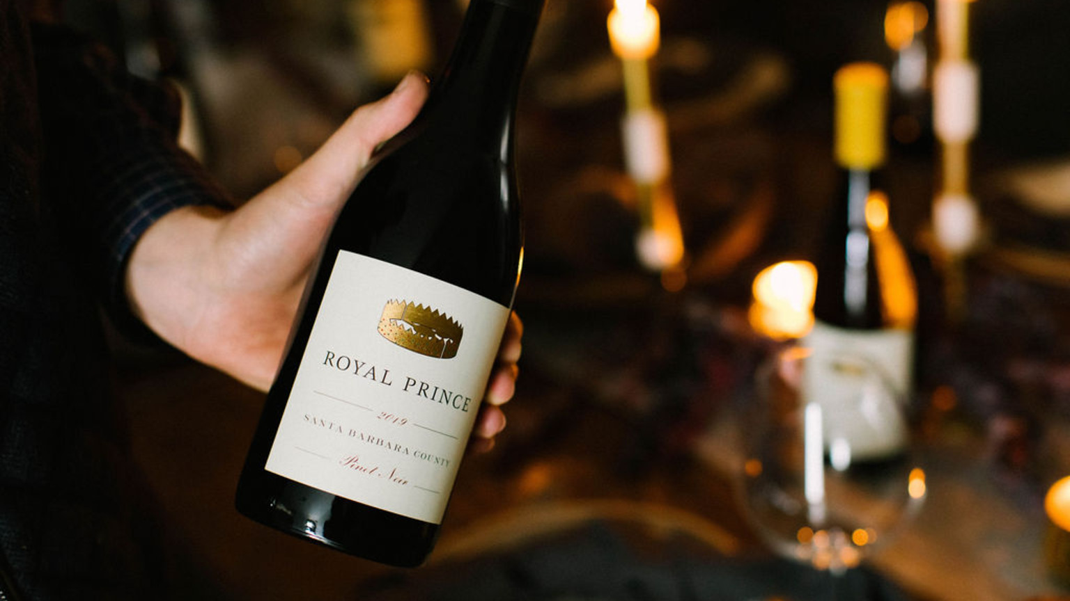 A hand presenting a bottle of 2021 Royal Prince Reserve Cabernet Sauvignon