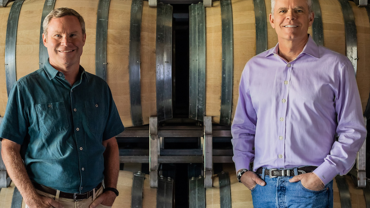 Two men in front of stacked barrels at Silver Oak