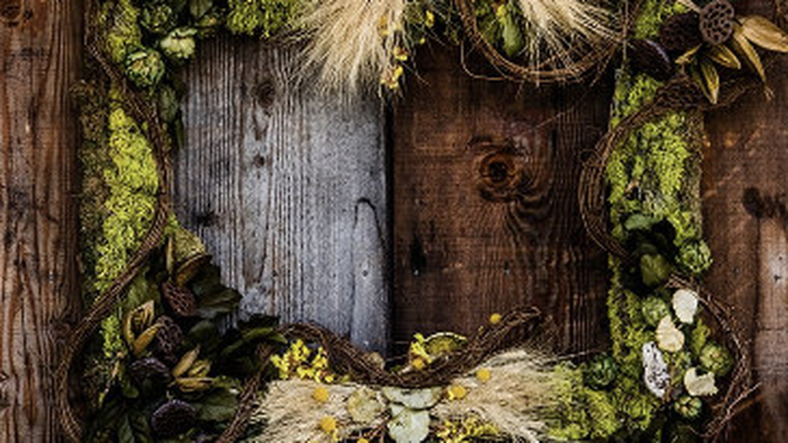 A wreath of moss, grain, and vines forming the Ovid mark on a wood wall
