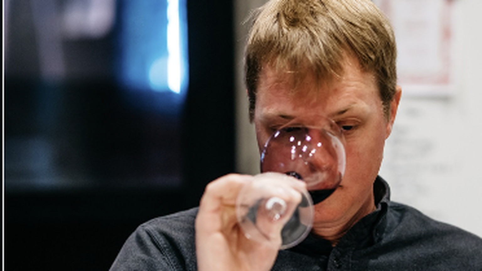 Austin Peterson tasting a red wine, with glasses lined up in front of him
