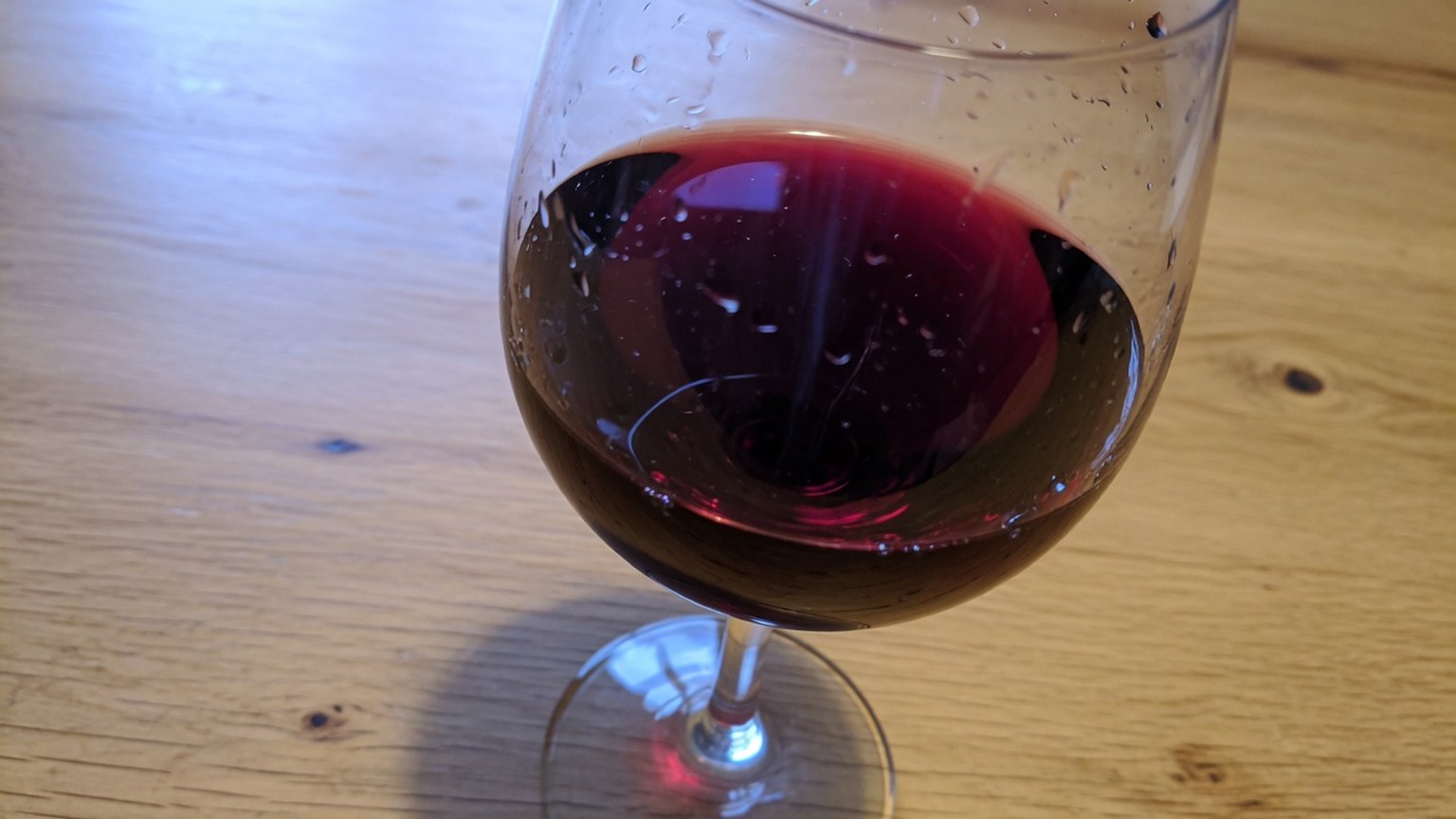 A glass of deep red wine on a wood table