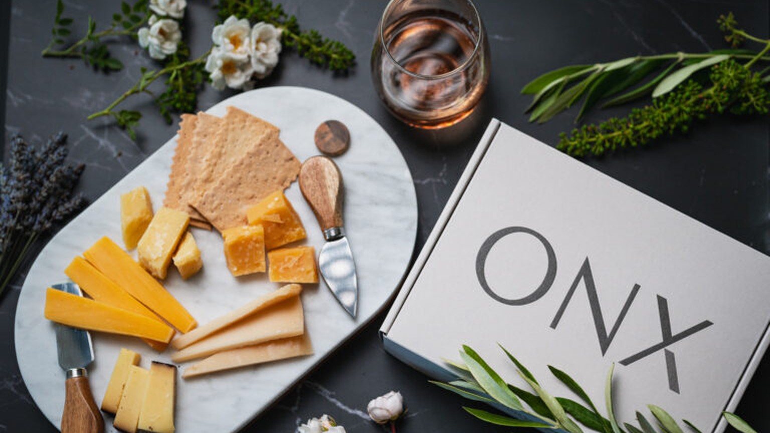 ONX gift box with cheese and rose on a vineyard table