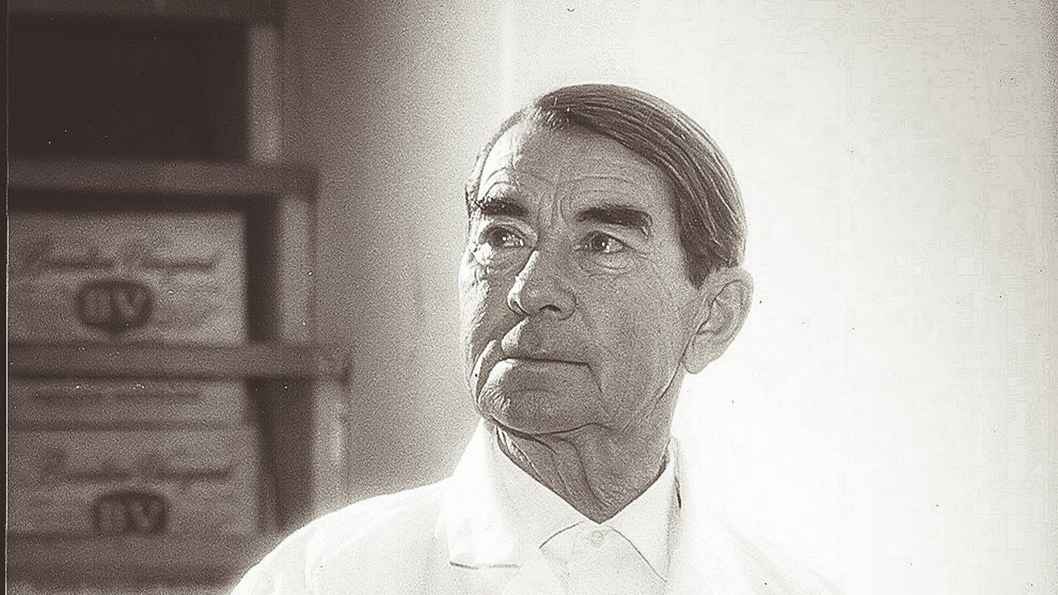 Portrait of André Tchelistcheff in a white cellar coat, hands clasped