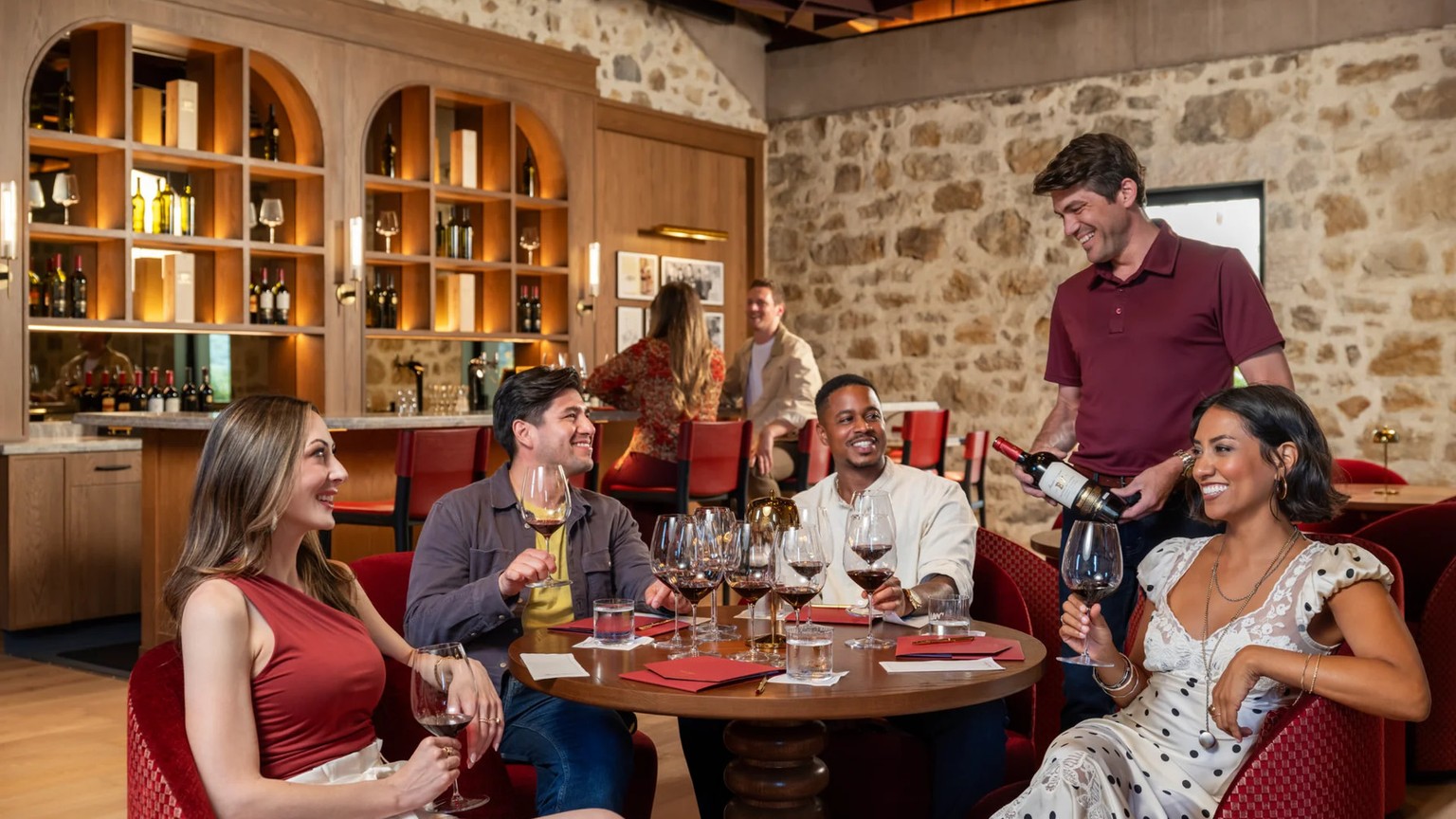 Guests in the Beaulieu tasting room with glasses of red wine and a bottle being poured