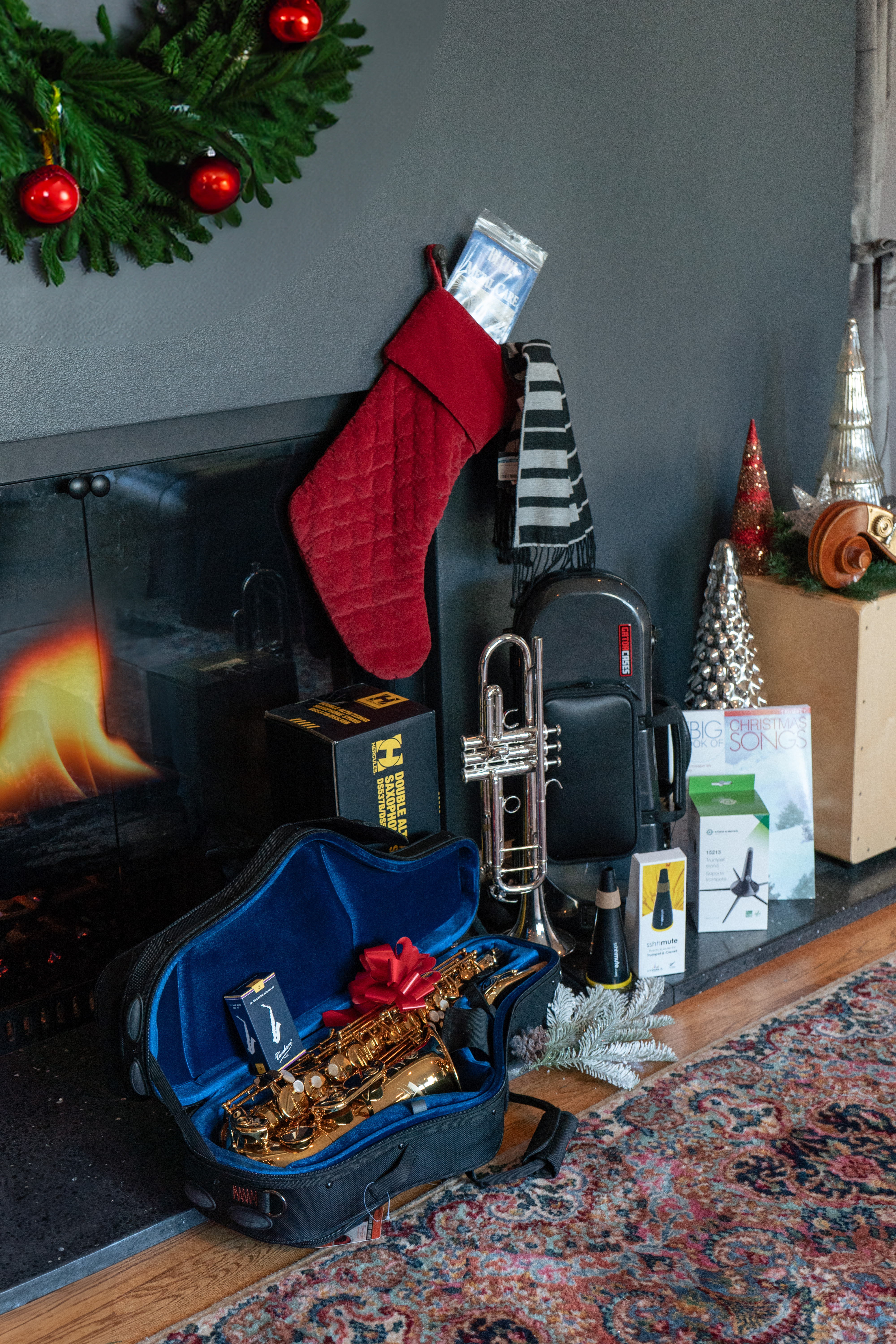 Trumpet and saxophone by the fireplace with assorted gifts and holiday decor.