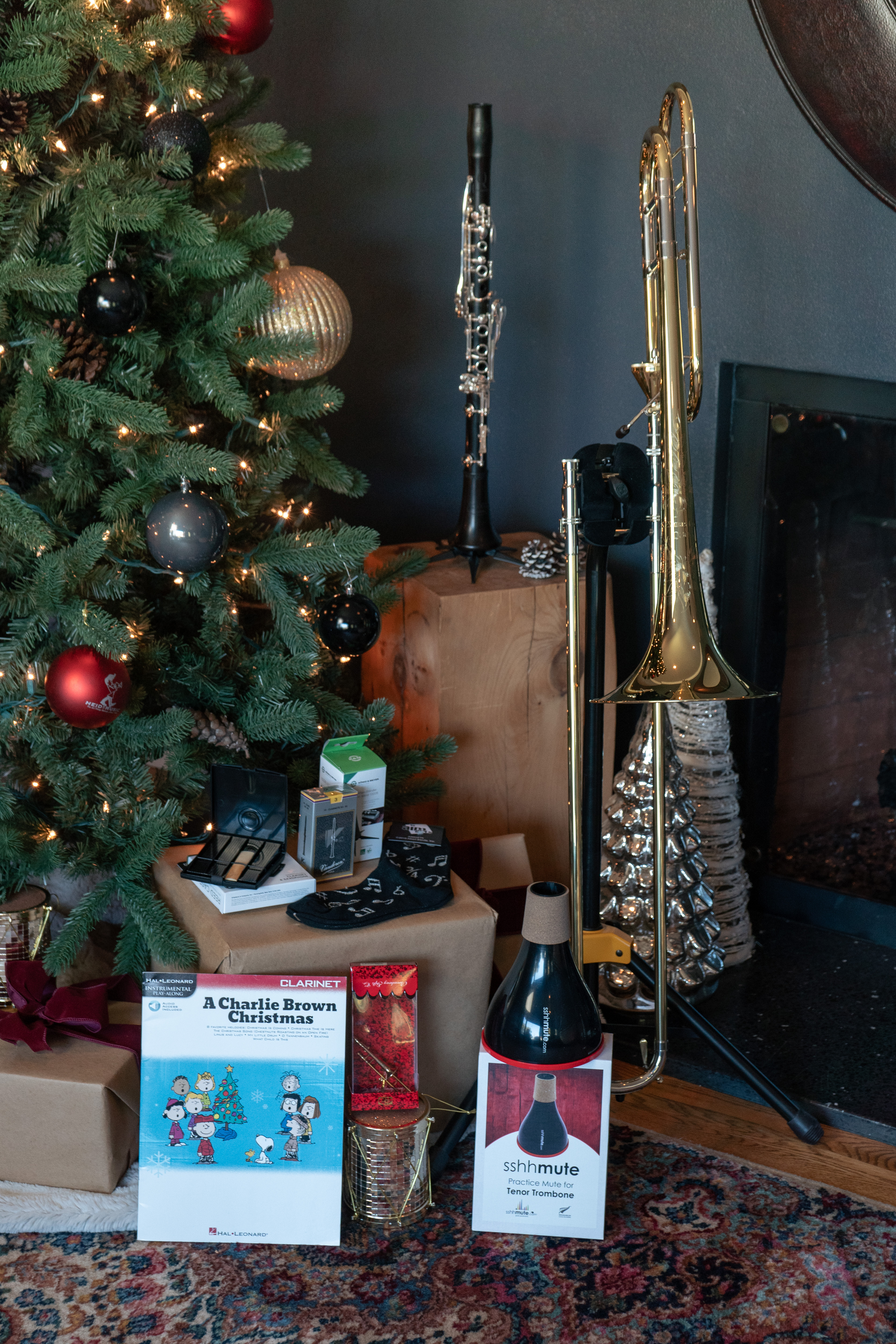 Clarinet and trombone next to a Christmas tree with assorted gifts and accessories.
