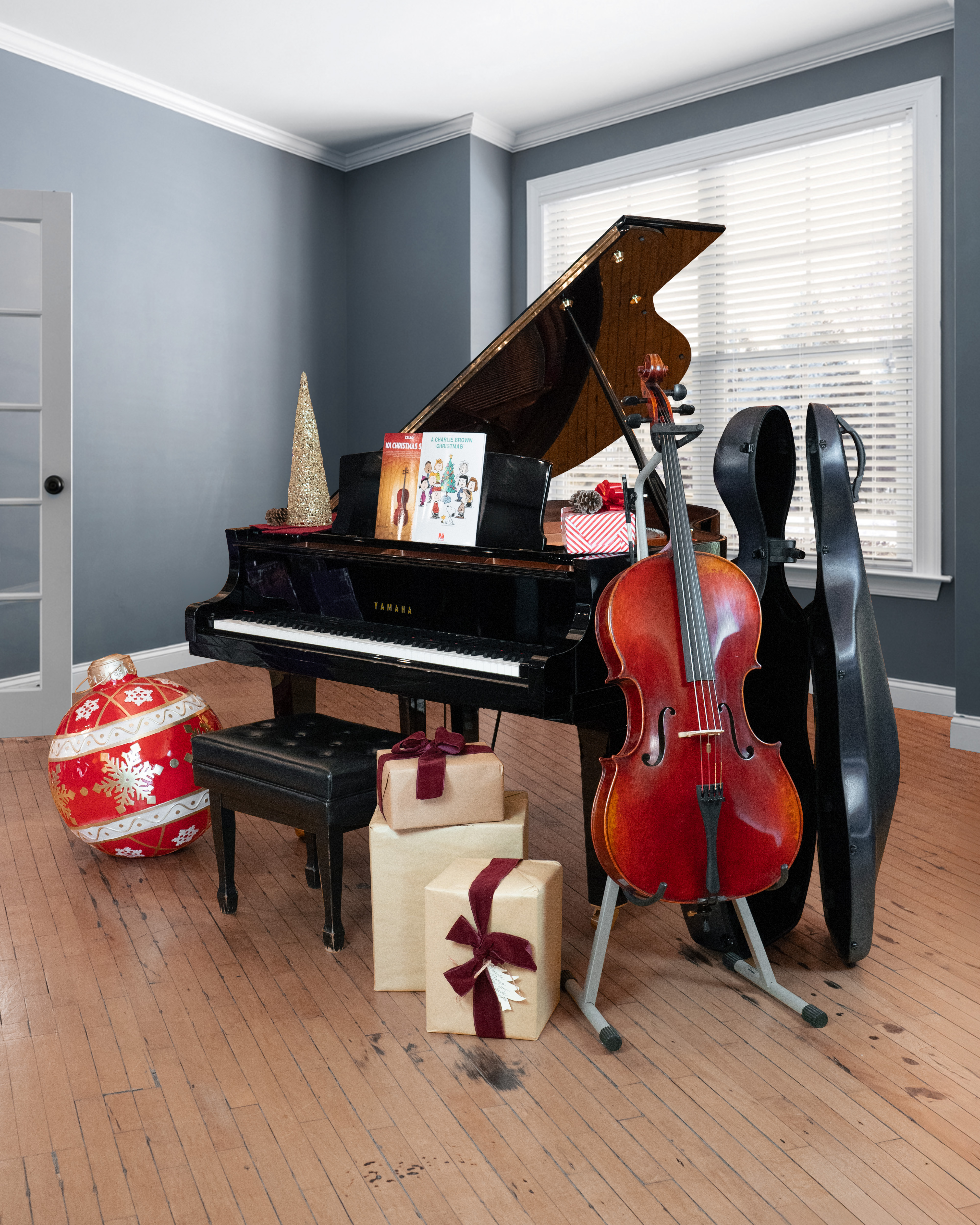 A Yamaha CX1 grand piano with an Eastman VC605S cello are surrounded by Christmas gifts and decorations