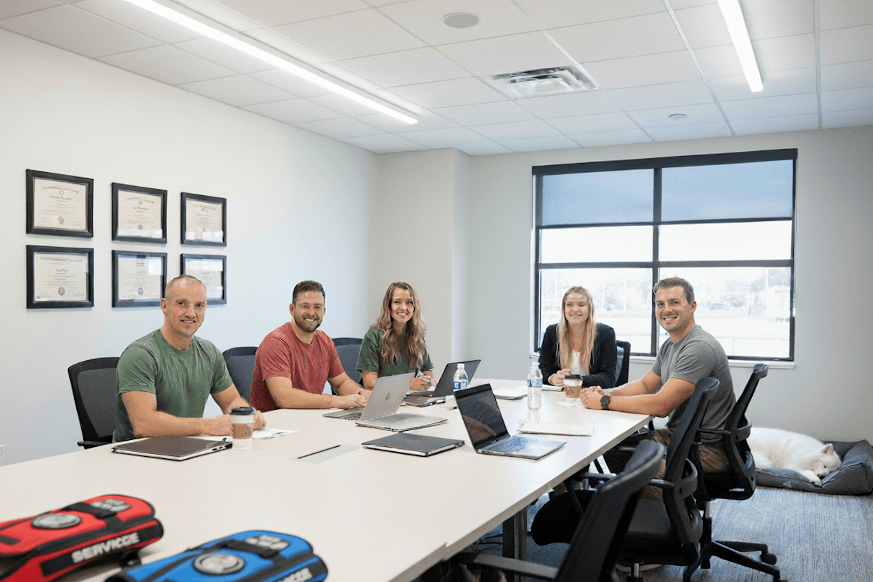 Five staff members meeting at conference table and smiling at Working Service Dog office