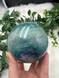 Discover an XL Rainbow Fluorite Sphere with stunning green, blue and purple tones and natural rainbow flash. A unique collector’s crystal for clarity and balance.