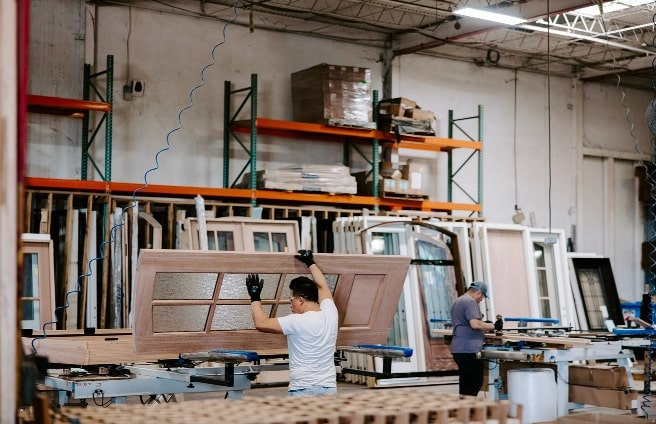 Workers assembling custom wood doors inside a manufacturing workshop