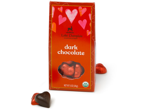 Organic dark chocolate hearts wrapped in red foils and packaged in a red Valentine's Day themed gift box with pink and red hearts and wrapped and unwrapped chocolate hearts around the box. View Product Image
