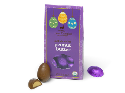 Milk chocolate peanut butter filled eggs wrapped in purple foils and packaged in an environmentally friendly Easter themed gift box, with wrapped and unwrapped chocolates eggs around the box.