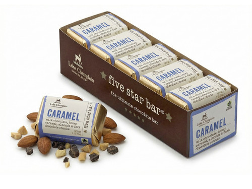 Ten milk chocolate caramel five star bars sitting in a long rectangular box with a caramel five star bar sitting on the left of the box with pieces of chocolate and almonds around the bar.