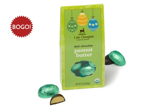 Dark chocolate peanut butter filled Easter eggs wrapped in green foils and packaged in a green, Easter themed gift box, with wrapped and unwrapped eggs sitting outside of the gift box and a red star burst sitting next to the egg box that says "BOGO" in white lettering