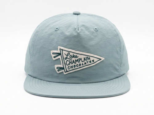 Image looking straight on of sage green surf hat with a cream color felt patch in the shape of a pennant that says "Lake Champlain Chocolates".