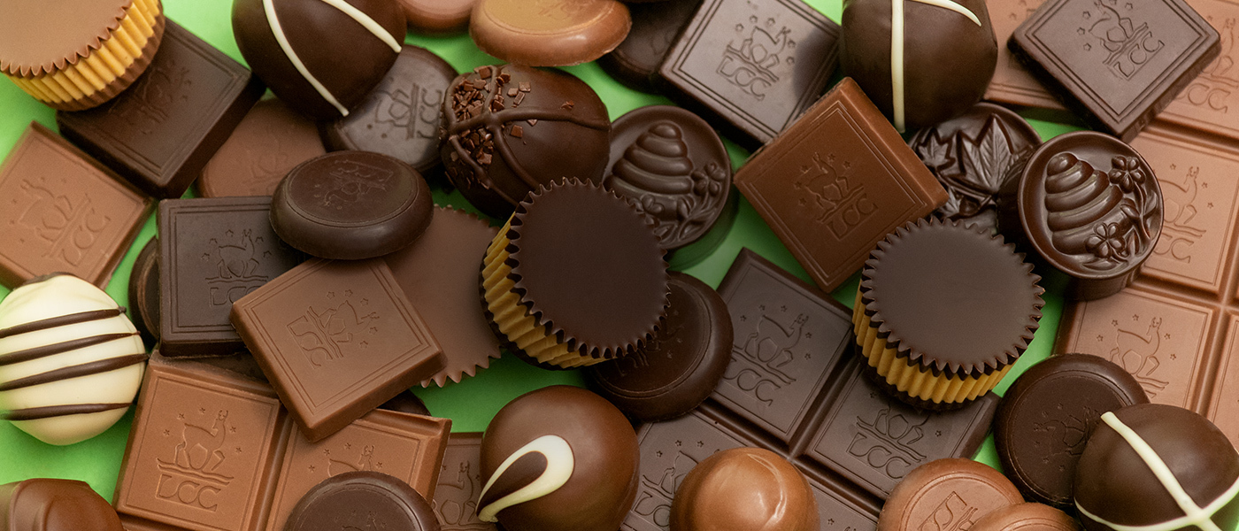 Assorted milk and dark chocolates gathered in a pile on a lime green background.