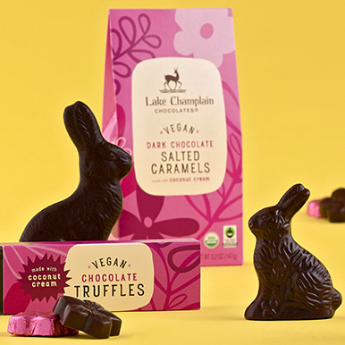 Assorted vegan truffles, salted caramel flowers, and dark chocolate Easter bunnies against a yellow background.