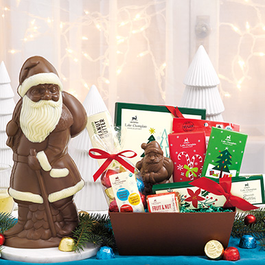 Assorted best selling Christmas chocolates on a teal tablecloth with white ceramic trees in the background.