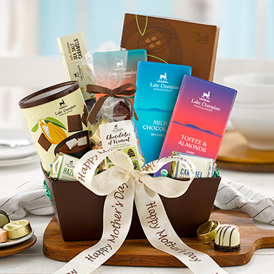 Assorted gurmet chocolates in a brown gift basket with a cream ribbon that says "Happy Mother's Day".