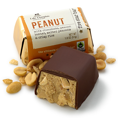 Milk chocolate Peanut Five Star Bar with an unwrapped bar sitting in front of the wrapped bar with pieces of peanuts around each bar.