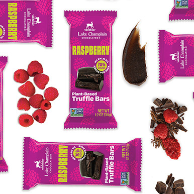 Raspberry plant-based truffle bars on a white background with a pile of raspberries and raspberries and pieces of chocolate next to the bars.