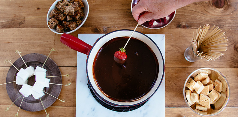 dipping strawberries in a pot of chocolate fondue