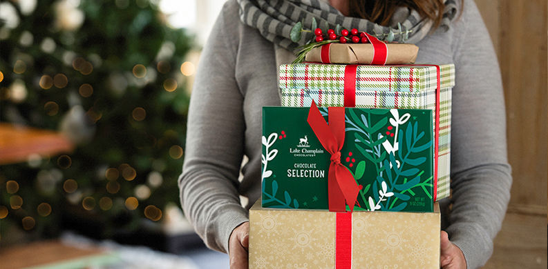 holding a stack of holiday chocolate gifts