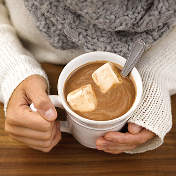 hands holding a mug of hot chocolate with marshmallows