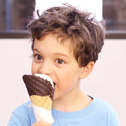 boy eating an ice cream from a chocolate dipped waffle cone