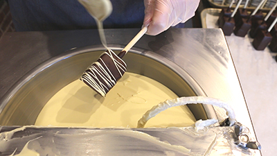 drizzling white chocolate on marshmallow pops