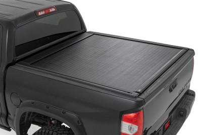 Every truck owner knows the importance of securing and protecting their gear, especially when conquering trails or venturing into the wild. With the Powered Retractable Bed Cover for the Toyota Tundra, you not only shield your equipment from unpredictable weather but also add an unmatched layer of security and style to your truck. Engineered with precision, this bed cover is designed to serve you whether you're cruising smooth highways or tackling rugged trails.Maximized Bed Access: The cover rolls smoothly to provide nearly full bed access, allowing you to make the most of your truck's storage potential.Heavy-Duty Aluminum Construction: Built tough with a rugged aluminum frame and sleek matte black finish, this bed cover is engineered to endure daily use and intense outdoor conditions without compromising on style.UV Protection for Long-Lasting Finish: Featuring built-in UV protection, the cover resists sun damage, keeping it looking brand new and preventing any fading over time.Lock Your Cover in Any Position: Thanks to its innovative electromagnetic brake system, you can lock the cover securely at any point along the rails, offering total flexibility for your storage needs.Remote Key Fob for Convenient Entry: Open or close your bed cover with just the push of a button using the integrated remote key fob, ensuring easy access even from a distance.Utility Rail with T-Slots: Enhance your storage options with the integrated utility rail, perfect for mounting racks and accessories to maximize your truck's versatility.Integrated Bed Rail Controls: Easily open and close the bed cover from the side rail for added convenience and quick access to your gear.Key Fob-Controlled LED Light Strip: The integrated LED light strip illuminates your truck bed, offering better visibility at night, controlled conveniently via the key fob.Auto-Locking Security: For added peace of mind, the bed cover features an auto-locking function, ensuring your cargo stays secure at all times.Rough Country's Powered Retractable Bed Cover combines style, security, and convenience, giving you the confidence that your truck is looking its best while your gear stays protected.