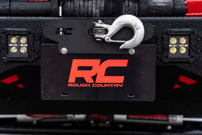 Take your vehicle from street legal to trail ready in a split second with Rough CountryΓÇÖs Quick Release Hawse Fairlead License Plate Mount. Front mounted license plates tend to stick out and can be prone to trail damage, especially on high clearance or low profile aftermarket bumpers, but many solutions require you to unbolt them from the vehicle before you take to the trails. This innovative license plate mount uses the tension from your spooled-in winch to hold your front plate perfectly in place. When you need to remove it, simply unspool the winch slightly and remove the entire plate!\
Before you head back out on the highway, simply slip back into position, spool in your winch, and youΓÇÖre ready to roll.This lightning-fast add-on stays put perfectly, even at top speeds and wind resistance, so you can hit the road with peace of mind!