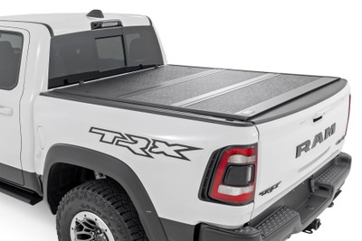 Rough Country's Hard Low-Profile Bed Cover is built for adventure. This tri-fold tonneau cover delivers a streamlined design that enhances your truck's off-road look while safeguarding your gear. Enjoy the peace of mind that comes with Rough Country's quality construction and easy access features. Here's what makes this tri-fold tonneau cover the ultimate winner:Low Profile, Sleek Look: Ditch the bulky covers! Our low-profile design seamlessly integrates with your truck bed, adding a touch of style without sacrificing function.Folds for Easy Access: Need to grab your gear in a hurry? No sweat! This tri-fold design lets you open the cover partially or fully in seconds, so you can access your truck bed whenever you need to.Extra Security: Worried about leaving your tools or weekend essentials behind? This cover integrates with your truck's tailgate lock, so you can relax knowing your gear is safe from prying eyes.Easy Does It Installation: We get it; you'd rather be out on the trails than wrestling with instructions. That's why our Bed Cover is designed for a simple, hassle-free installation. You'll be cruising with newfound bed security in no time!Built to Last: Rough Country backs this tonneau cover with a 5-Year Warranty, so you can rest assured it's ready to conquer any adventure.Streamline your truck bed, secure your gear, and hit the trails with peace of mind. Rough Country's Hard Low-Profile Bed Cover is the perfect solution for those who demand both style and functionality.