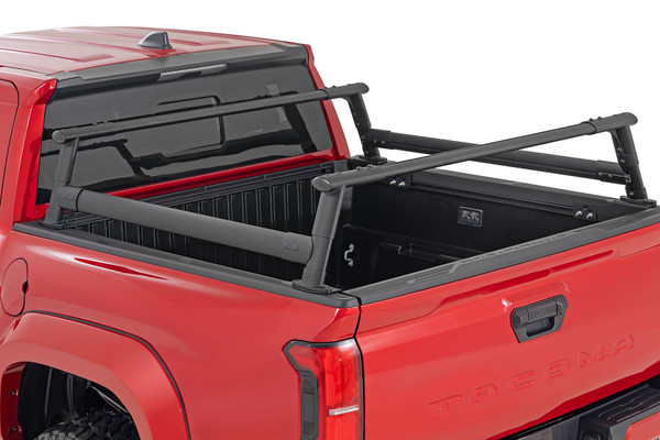 Upgrade your Tacoma Bed. The Tacoma Bed Rack from Rough Country gives you the flexibility to carry bulky cargo and outdoor equipment in your truck bed. It's just right for loading ladders, roof racks, bikes, and more with ease. And whether you're headed out for a camping trip or working under the sun on a job site, this bed rack keeps all your equipment close at hand.\
Durable Style: This innovative bed rack system is built from durable powder-coated aluminum for lightweight strength and durability. The modular design allows you to add as many crossbars as needed, and the molded end caps and T-slot covers give your truck that clean look you're looking for. Rugged enough to handle any payload you can throw at it; our bed rack is sure to turn headsΓÇöand help you carry your gear wherever you need it.\
Installation and Warranty: This easy-to-install rack offers endless mounting options and adjustability, so you can customize it to suit your specific needs. It also retains rear visibility, making it the perfect choice for those who want to maintain a clear view while driving. Plus, it comes with Rough Country's Limited Lifetime Warranty, so you can rest assured that it's built to last. So, load up and hit the road with confidence, knowing that Rough Country has you covered.