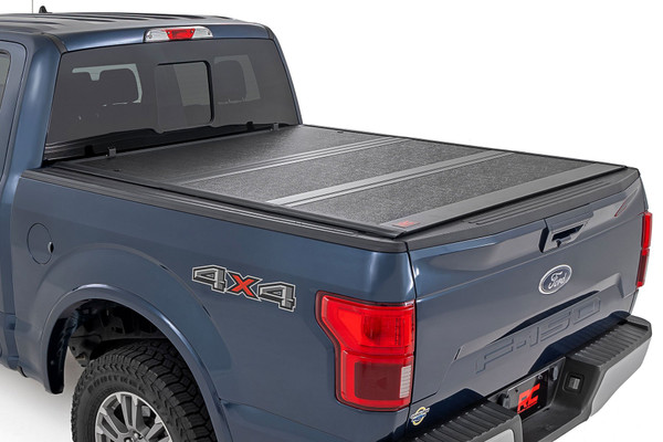 Rough Country's Hard Low-Profile Bed Cover is built for adventure. This tri-fold tonneau cover delivers a streamlined design that enhances your truck's off-road look while safeguarding your gear. Enjoy the peace of mind that comes with Rough Country's quality construction and easy access features. Here's what makes this tri-fold tonneau cover the ultimate winner:Low Profile, Sleek Look: Ditch the bulky covers! Our low-profile design seamlessly integrates with your truck bed, adding a touch of style without sacrificing function.Folds for Easy Access: Need to grab your gear in a hurry? No sweat! This tri-fold design lets you open the cover partially or fully in seconds, so you can access your truck bed whenever you need to.Extra Security: Worried about leaving your tools or weekend essentials behind? This cover integrates with your truck's tailgate lock, so you can relax knowing your gear is safe from prying eyes.Easy Does It Installation: We get it; you'd rather be out on the trails than wrestling with instructions. That's why our Bed Cover is designed for a simple, hassle-free installation. You'll be cruising with newfound bed security in no time!Built to Last: Rough Country backs this tonneau cover with a 5-Year Warranty, so you can rest assured it's ready to conquer any adventure.Streamline your truck bed, secure your gear, and hit the trails with peace of mind. Rough Country's Hard Low-Profile Bed Cover is the perfect solution for those who demand both style and functionality.