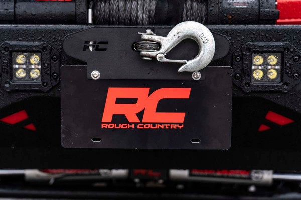 Take your vehicle from street legal to trail ready in a split second with Rough CountryΓÇÖs Quick Release Hawse Fairlead License Plate Mount. Front mounted license plates tend to stick out and can be prone to trail damage, especially on high clearance or low profile aftermarket bumpers, but many solutions require you to unbolt them from the vehicle before you take to the trails. This innovative license plate mount uses the tension from your spooled-in winch to hold your front plate perfectly in place. When you need to remove it, simply unspool the winch slightly and remove the entire plate!\
Before you head back out on the highway, simply slip back into position, spool in your winch, and youΓÇÖre ready to roll.This lightning-fast add-on stays put perfectly, even at top speeds and wind resistance, so you can hit the road with peace of mind!