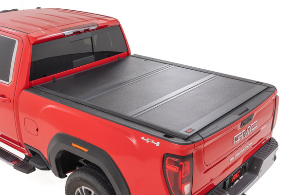 Rough Country's Hard Low-Profile Bed Cover is built for adventure. This tri-fold tonneau cover delivers a streamlined design that enhances your truck's off-road look while safeguarding your gear. Enjoy the peace of mind that comes with Rough Country's quality construction and easy access features. Here's what makes this tri-fold tonneau cover the ultimate winner:Low Profile, Sleek Look: Ditch the bulky covers! Our low-profile design seamlessly integrates with your truck bed, adding a touch of style without sacrificing function.Folds for Easy Access: Need to grab your gear in a hurry? No sweat! This tri-fold design lets you open the cover partially or fully in seconds, so you can access your truck bed whenever you need to.Extra Security: Worried about leaving your tools or weekend essentials behind? This cover integrates with your truck's tailgate lock, so you can relax knowing your gear is safe from prying eyes.Easy Does It Installation: We get it; you'd rather be out on the trails than wrestling with instructions. That's why our Bed Cover is designed for a simple, hassle-free installation. You'll be cruising with newfound bed security in no time!Built to Last: Rough Country backs this tonneau cover with a 5-Year Warranty, so you can rest assured it's ready to conquer any adventure.Streamline your truck bed, secure your gear, and hit the trails with peace of mind. Rough Country's Hard Low-Profile Bed Cover is the perfect solution for those who demand both style and functionality.