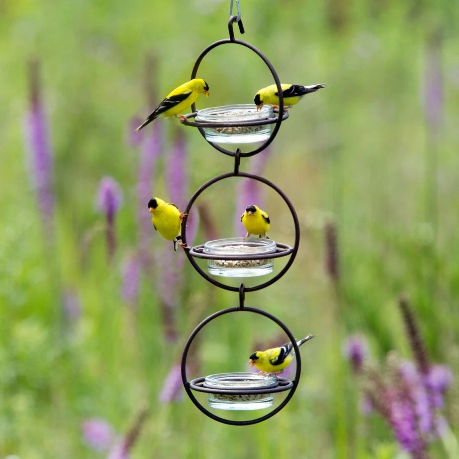 Multiple gold Hummble feeders connected vertically with birds feeding